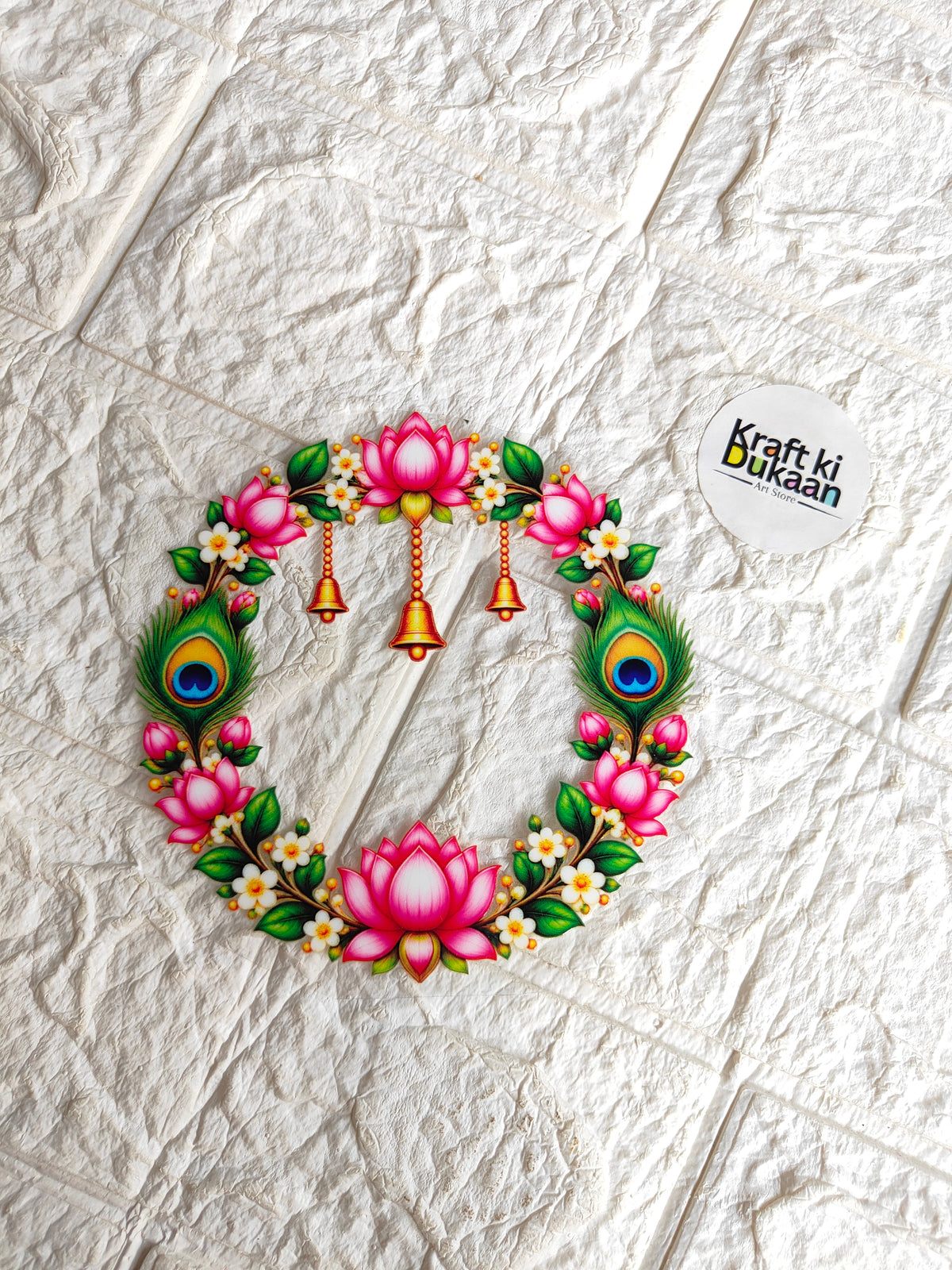 Round peel-off sticker showing pink lotus wreath with peacock-feather details and bells