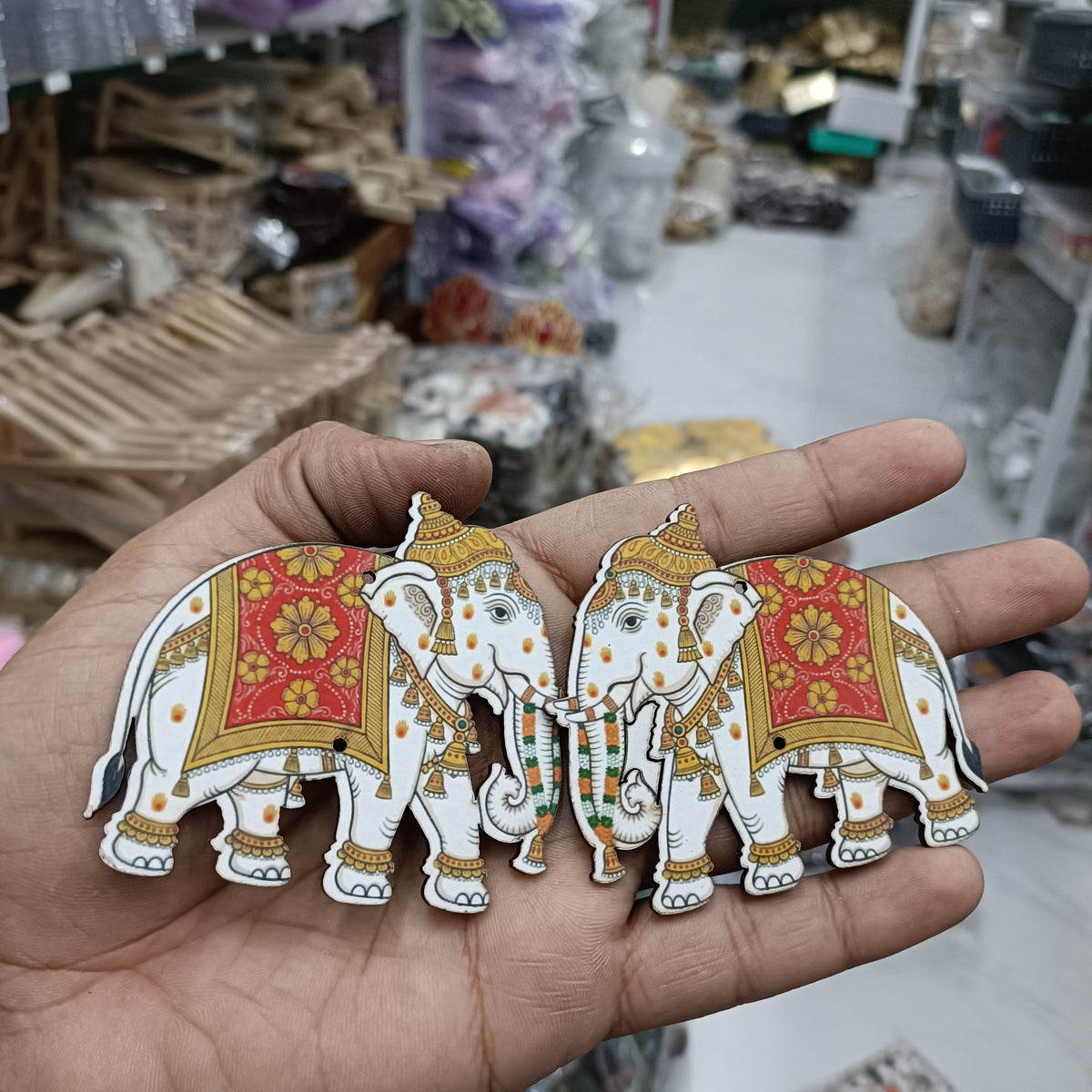 Two elephant MDF cutouts with patterned red panels and gold ornaments in hand