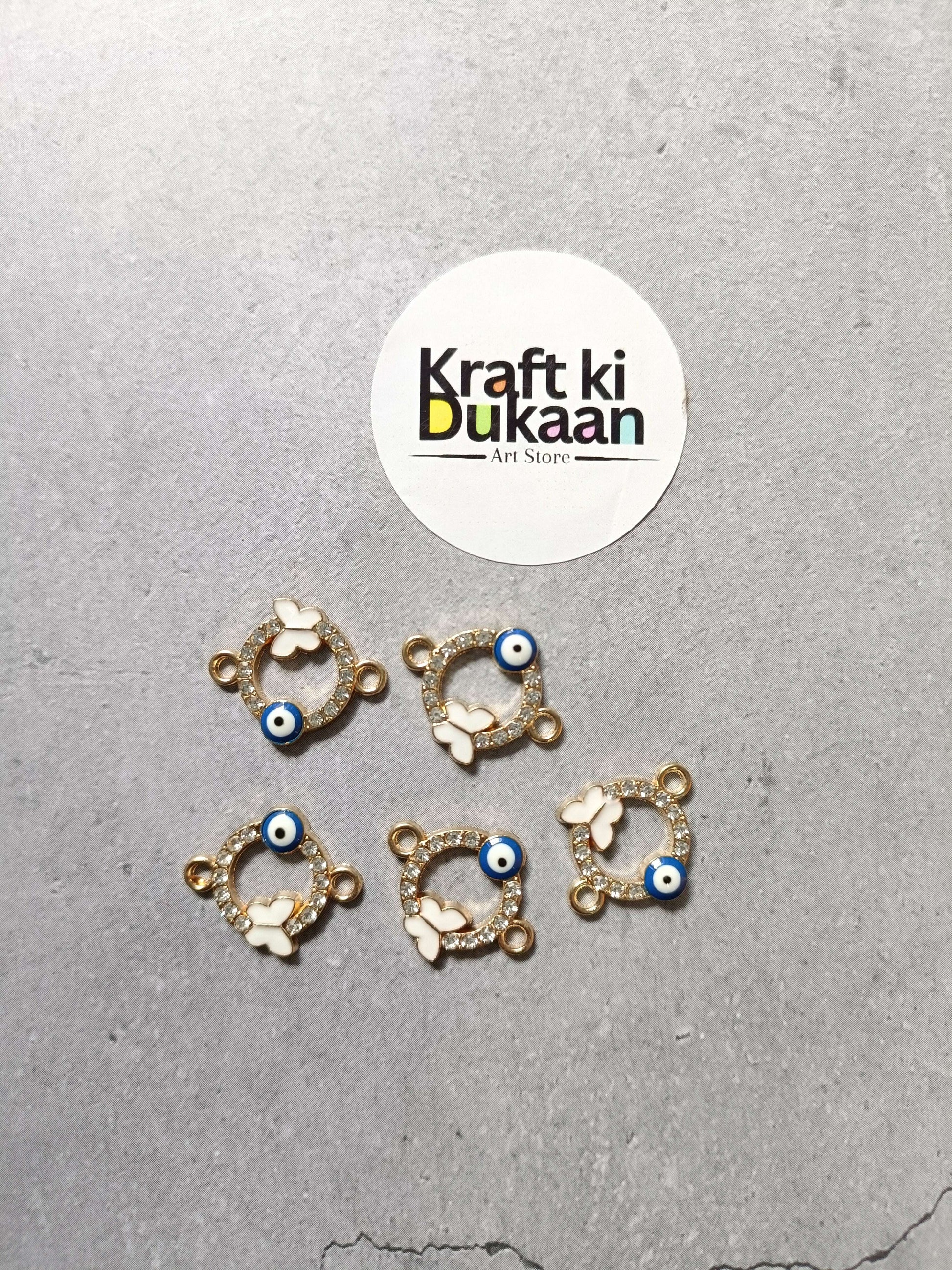 Five gold-tone evil eye bracelet charms, circular white butterfly details with blue bead
