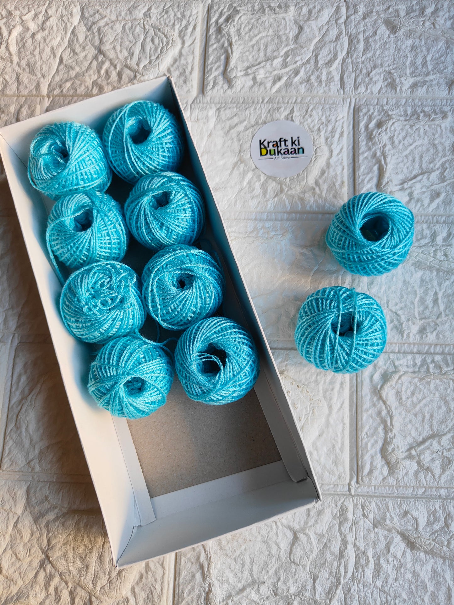 Rakhi thread roll set with light blue yarn balls in an open cardboard box