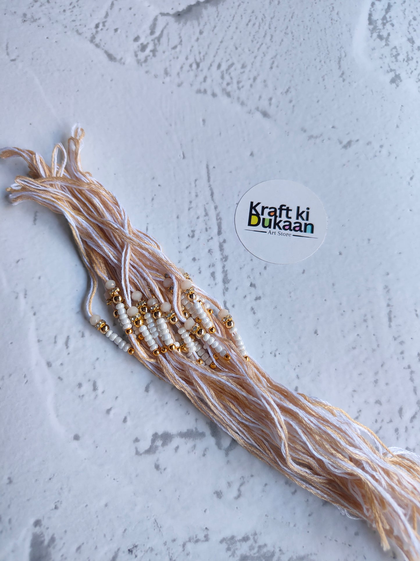 Beaded rakhi dori with off-white thread and gold accents