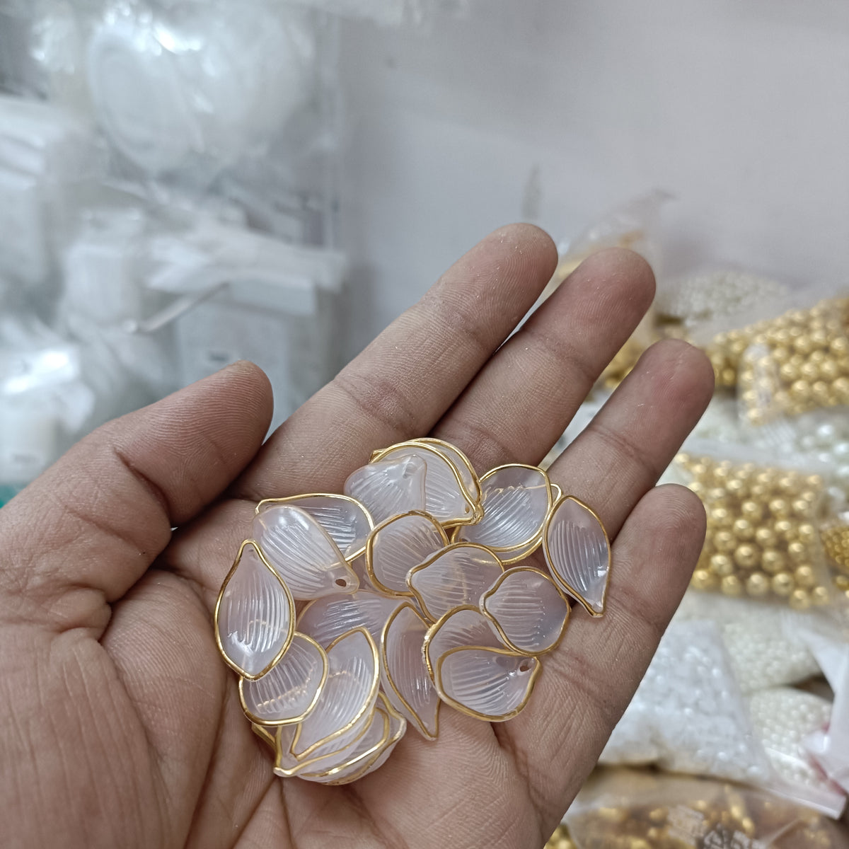 Gold-trim clear acrylic petal beads in hand, 50-pack, leaf-teardrop shape