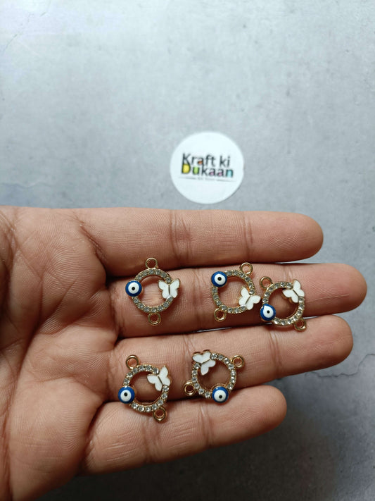 Gold-tone evil eye bracelet charms in hand, white butterfly motifs and blue eyes
