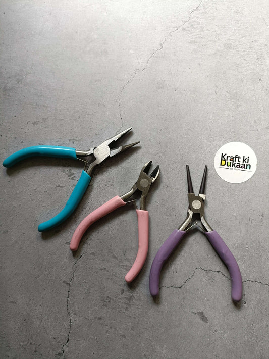 Three-piece pliers set with blue, pink, and purple insulated handles, side view