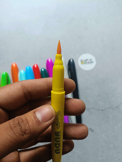 Yellow brush pen with angled tip, held in a hand