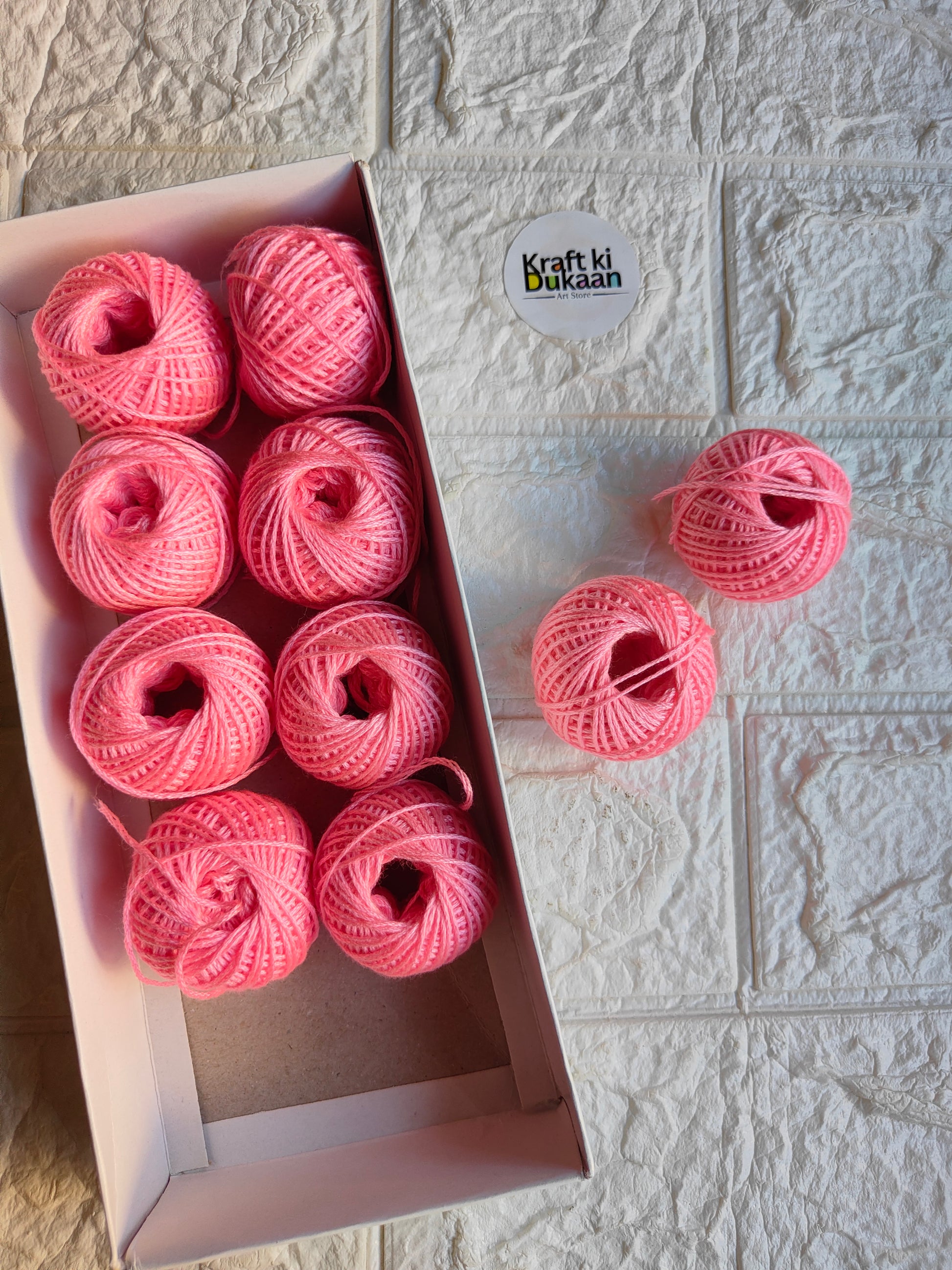 Rakhi thread roll with pink yarn balls in an open box and one loose ball