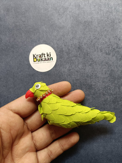 Green parrot figurine held in hand, red beak and jeweled collar