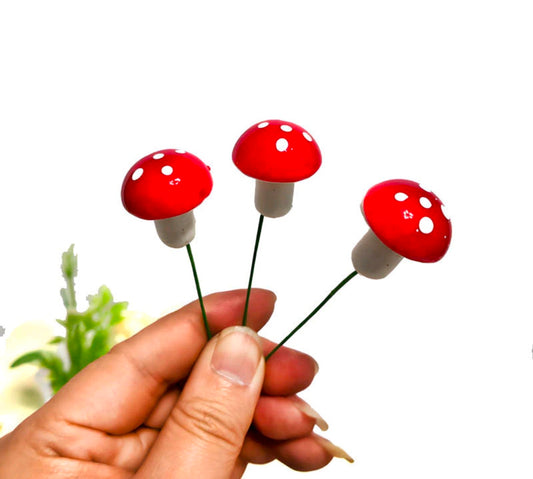Faux mushroom topper set with red caps and light stems, held in hand (3 pieces)