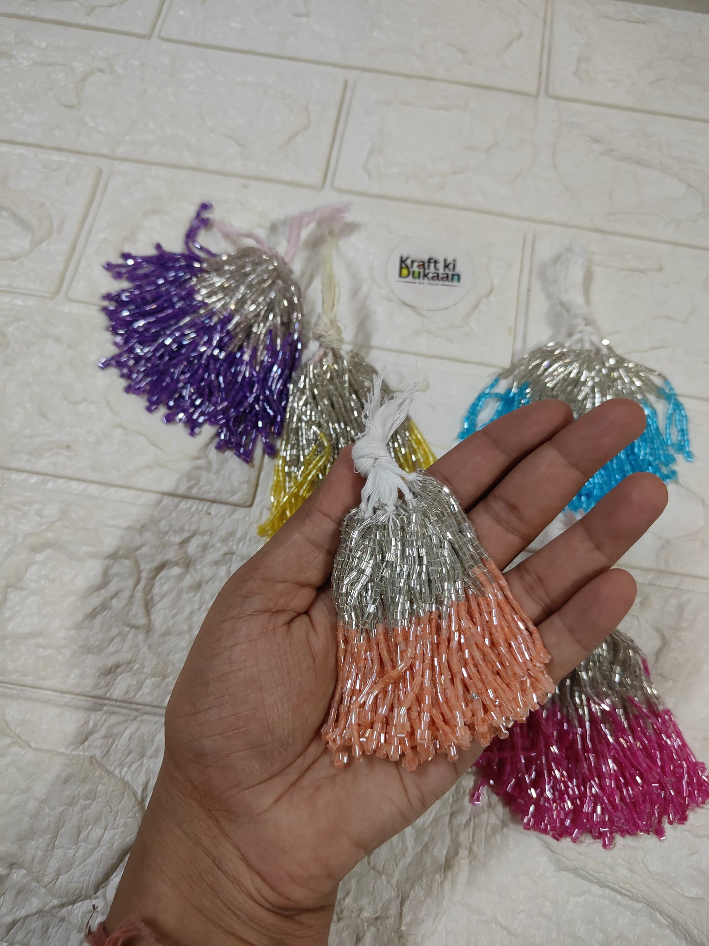 Set of 10 metallic latkan tassels held in hand: silver, orange, purple, blue and pink