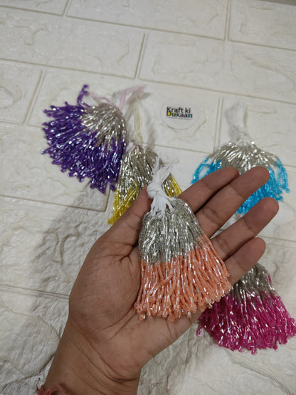 Set of 10 metallic latkan tassels held in hand: silver, orange, purple, blue and pink