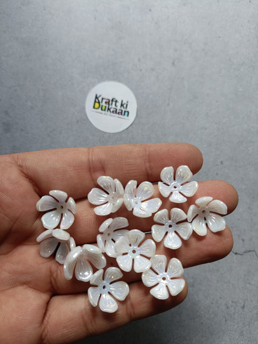 White five-petal flower beads with small round centers, held in hand