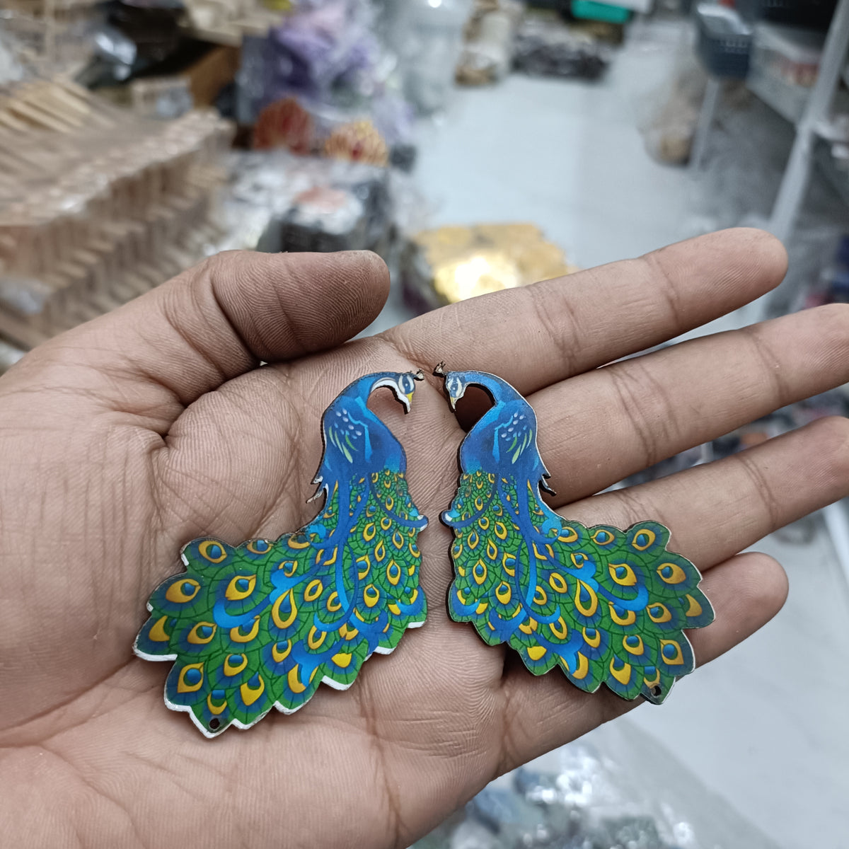 Peacock-shaped MDF cutout pair, blue and green feather design with white accents.