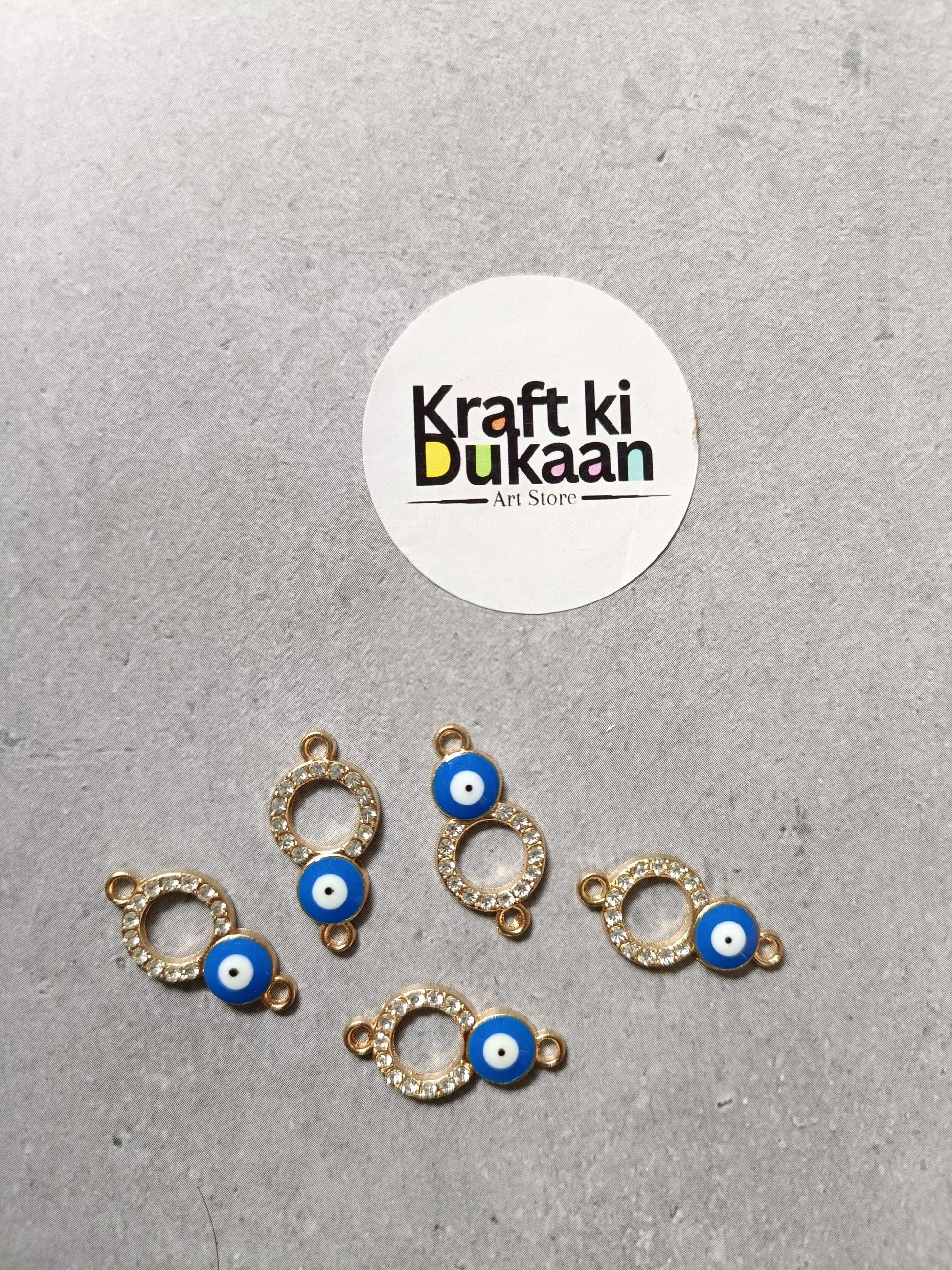 Five evil eye bracelet charms with gold-tone ring settings and blue eye beads, laid out
