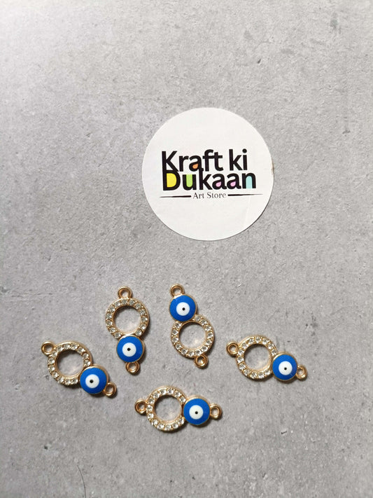 Five evil eye bracelet charms with gold-tone ring settings and blue eye beads, laid out