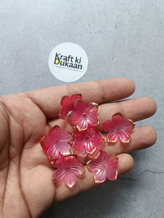 Red flower-shaped beads in hand, translucent pink petals with gold-tone loops