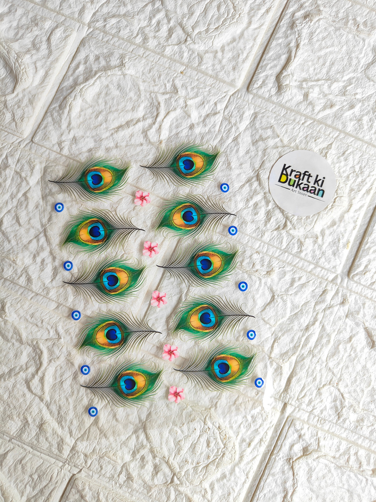Peacock feather eye peel-off sticker sheet with blue dots and pink accents on white backing
