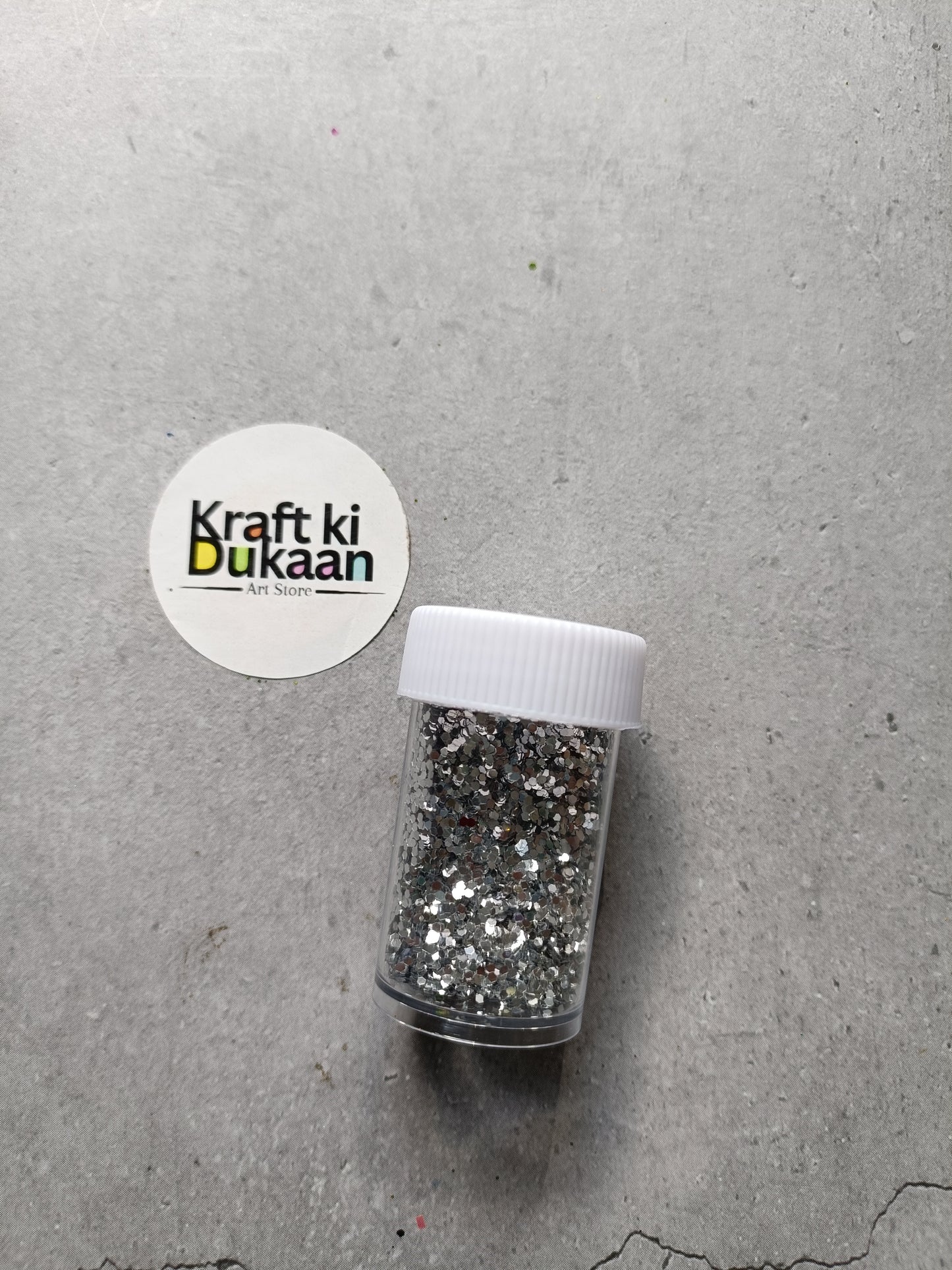Hexagon glitter jar with silver glitter in a small white-lidded bottle