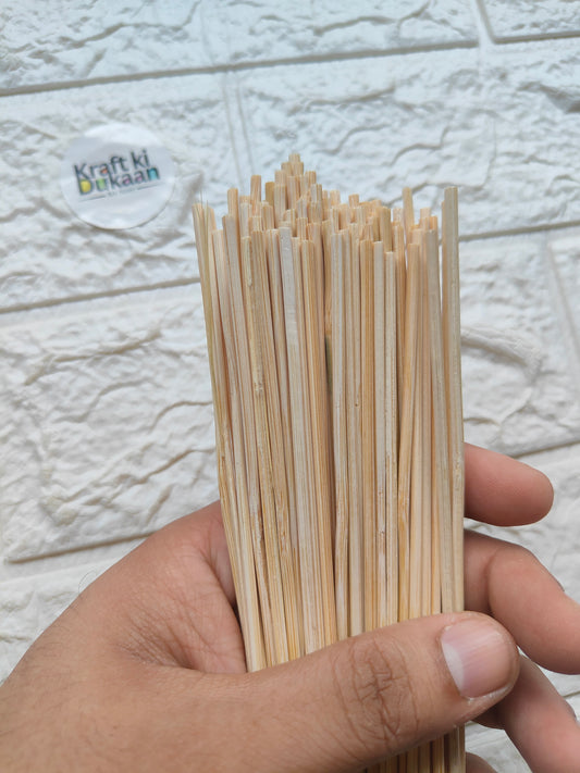 Set of light bamboo chopsticks showing close-up ends held between fingers