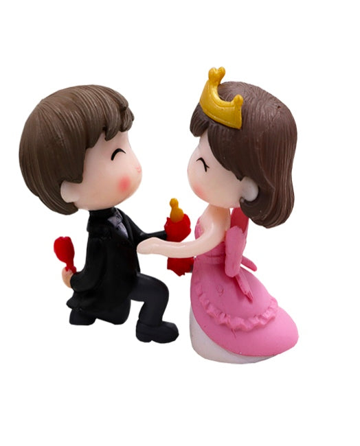 Miniature model couple figurines: black-suited man holding red hearts, pink-dress woman