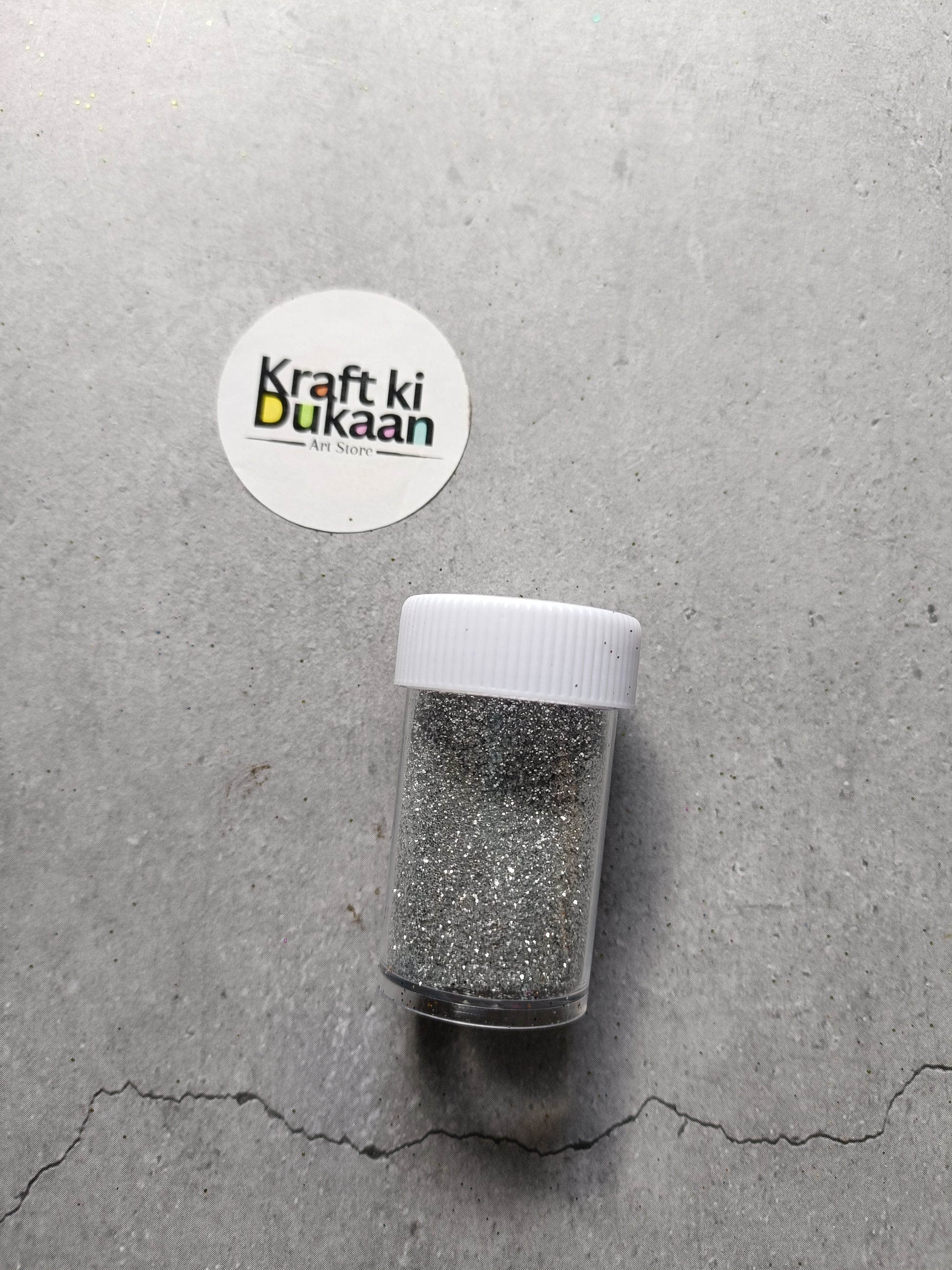 Silver chunky glitter powder in clear shaker bottle with white lid