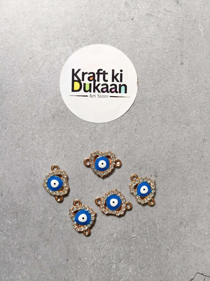 Five evil eye bracelet charms, blue center with gold-tone edging, arranged on surface