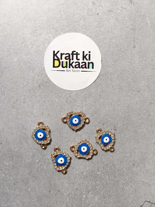 Five evil eye bracelet charms, blue center with gold-tone edging, arranged on surface