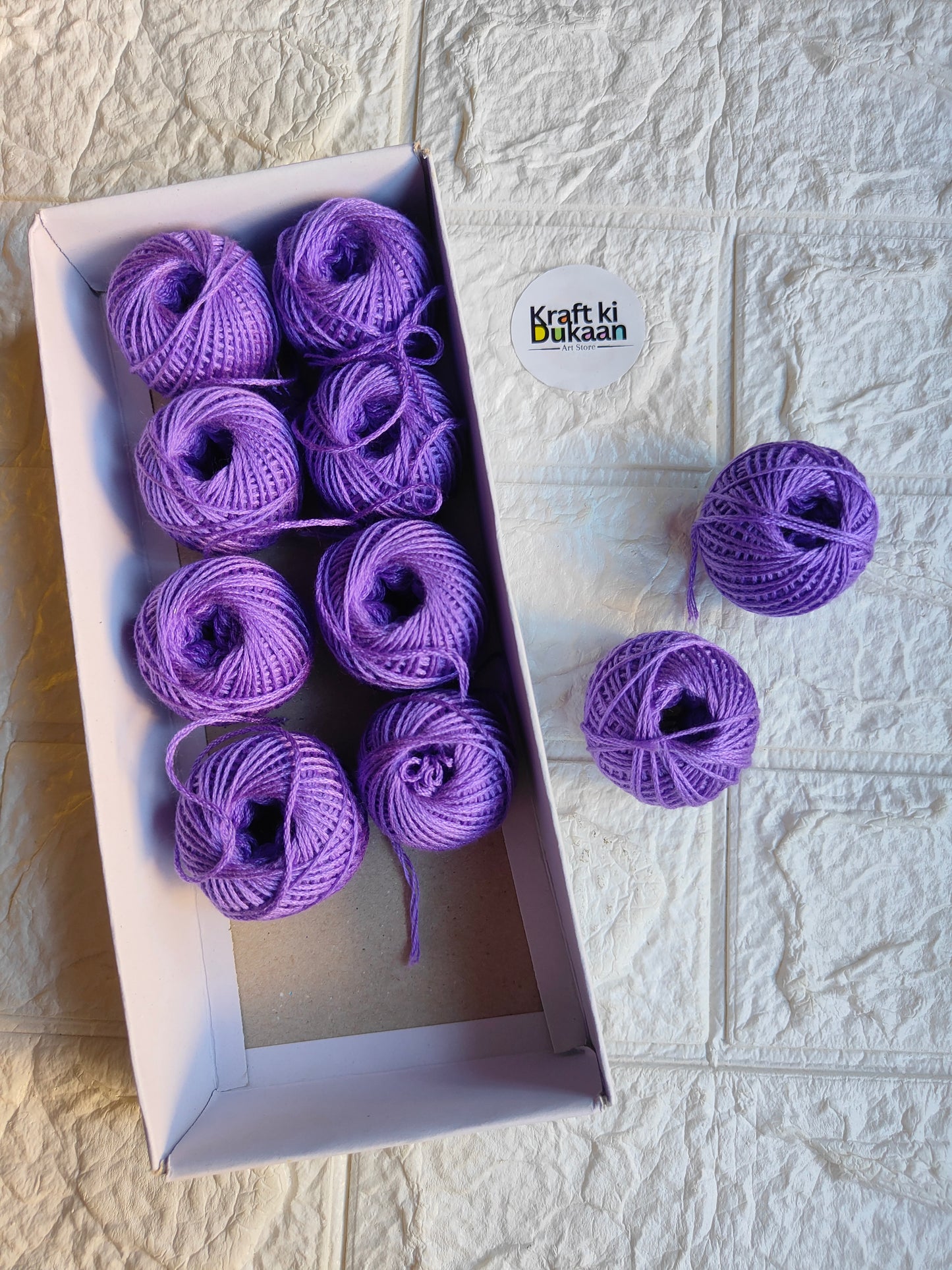 Rakhi thread roll set with purple yarn balls in an open cardboard box
