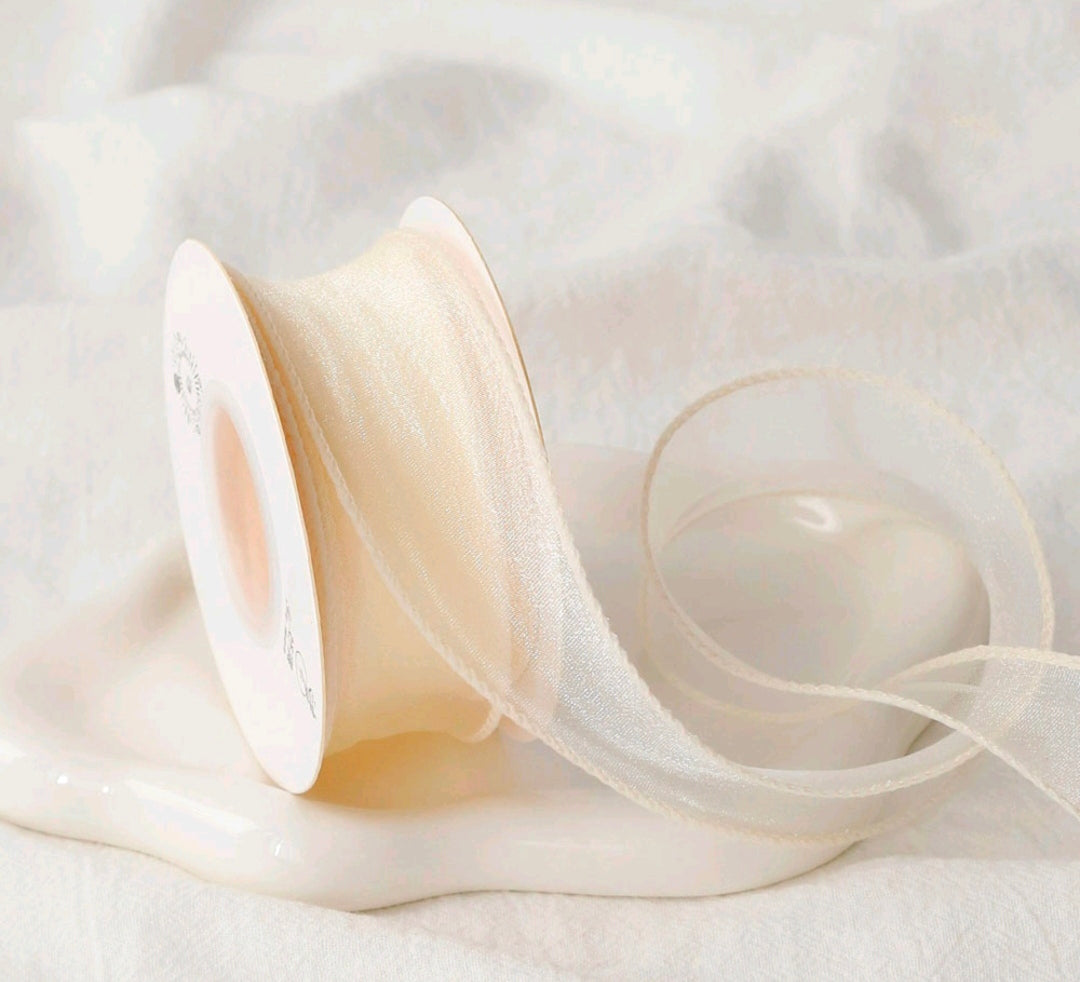 Off-white sheer net ribbon on a spool, crisscross texture with flowing edge