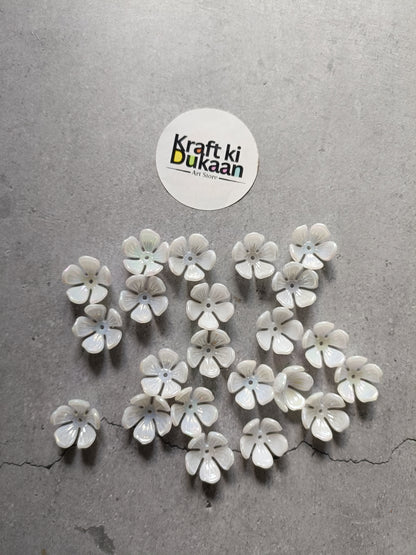 White flower-shaped beads scattered, small round petals with iridescent centers
