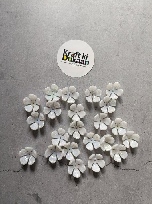 White five-petal flower beads with small round centers, scattered on surface