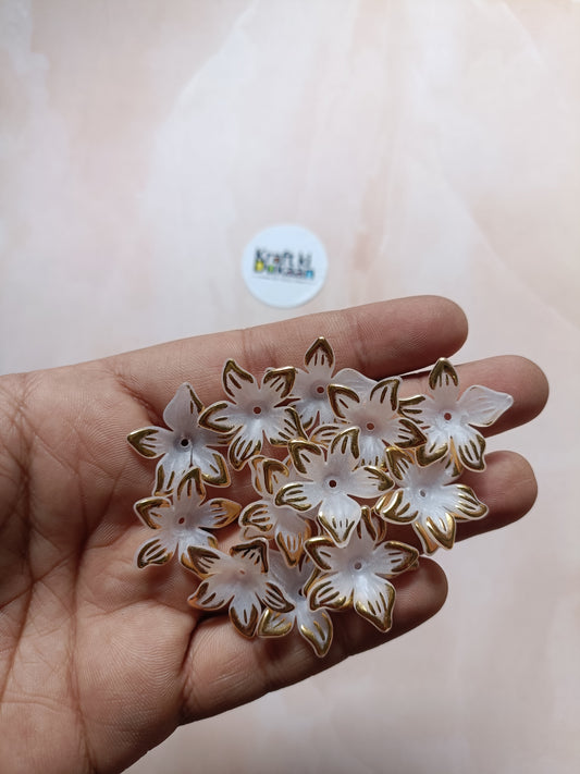 Flower bead charms, white petals with gold edging, held in hand