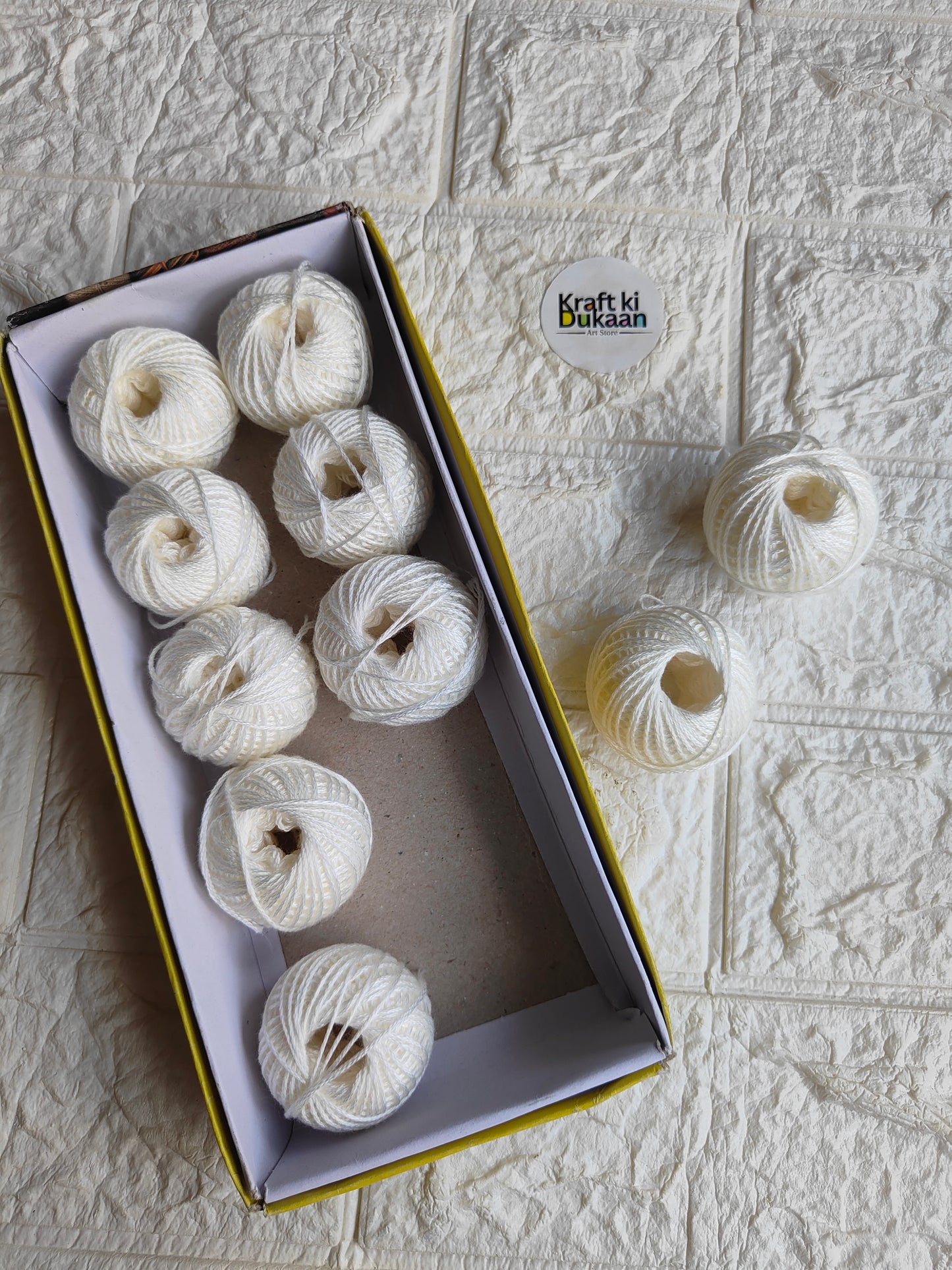 Rakhi thread roll with white thread balls in open box and one loose ball