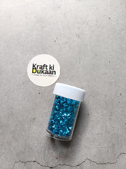 Hexagon glitter jar with aqua-blue glitter in a small white-lidded bottle
