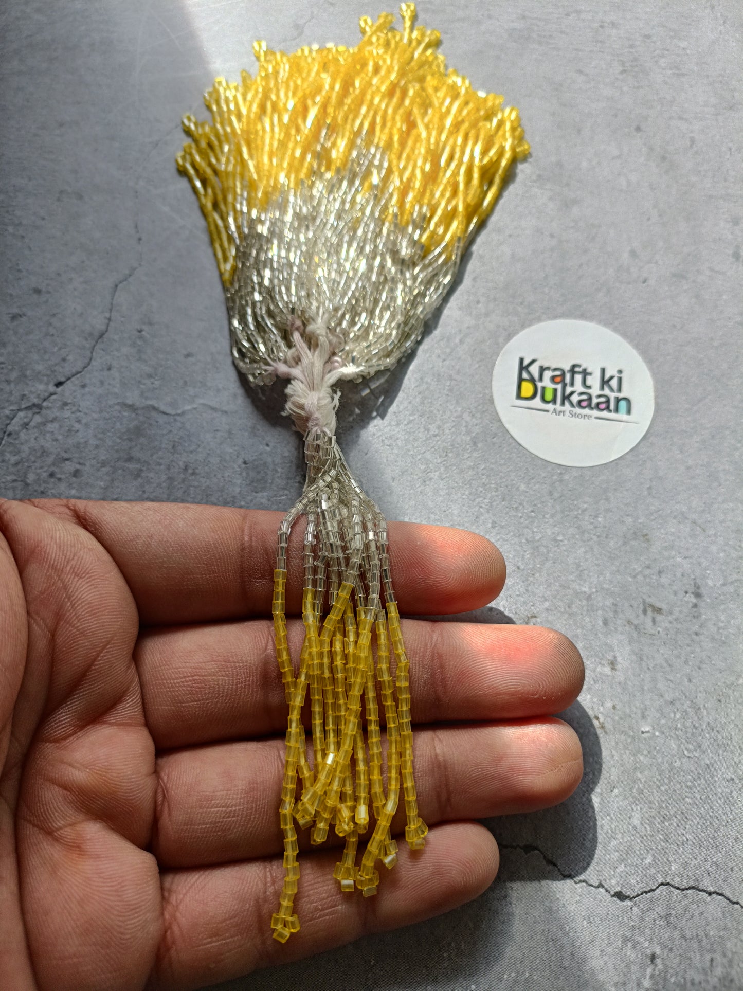 Small beaded tassel latkan with silver top and yellow fringe.