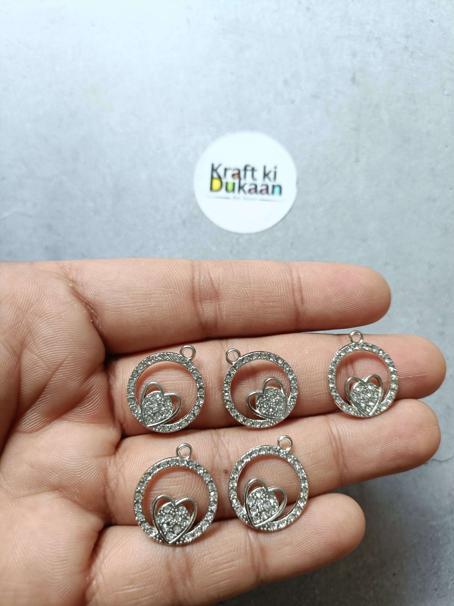 Heart motif round pendant charms in silver tone, 5-pack shown in hand