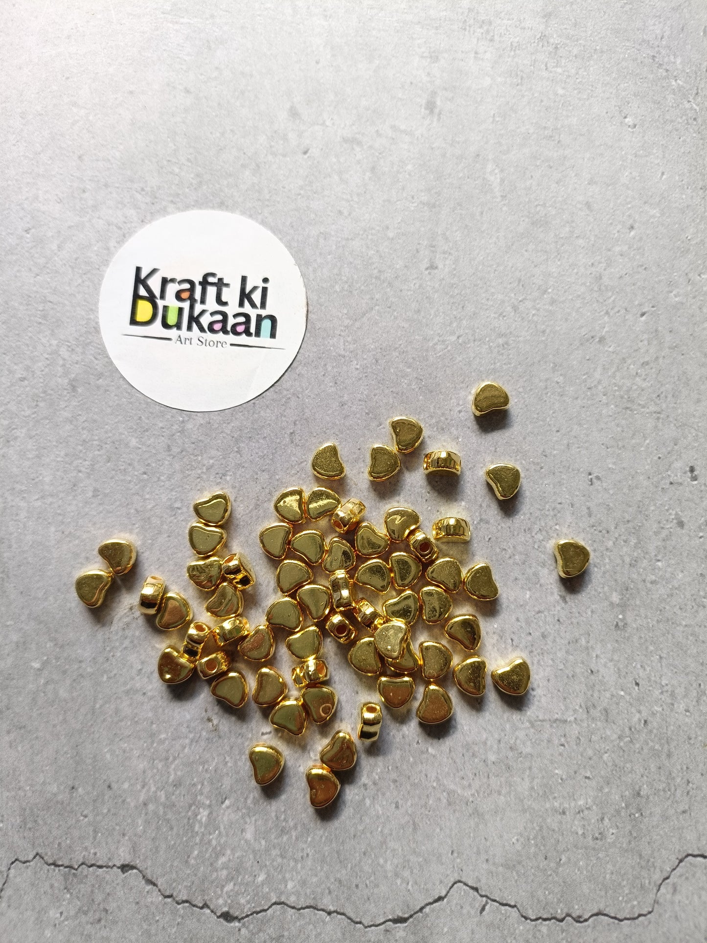 Golden heart-shaped small beads scattered, tiny metal craft pieces.