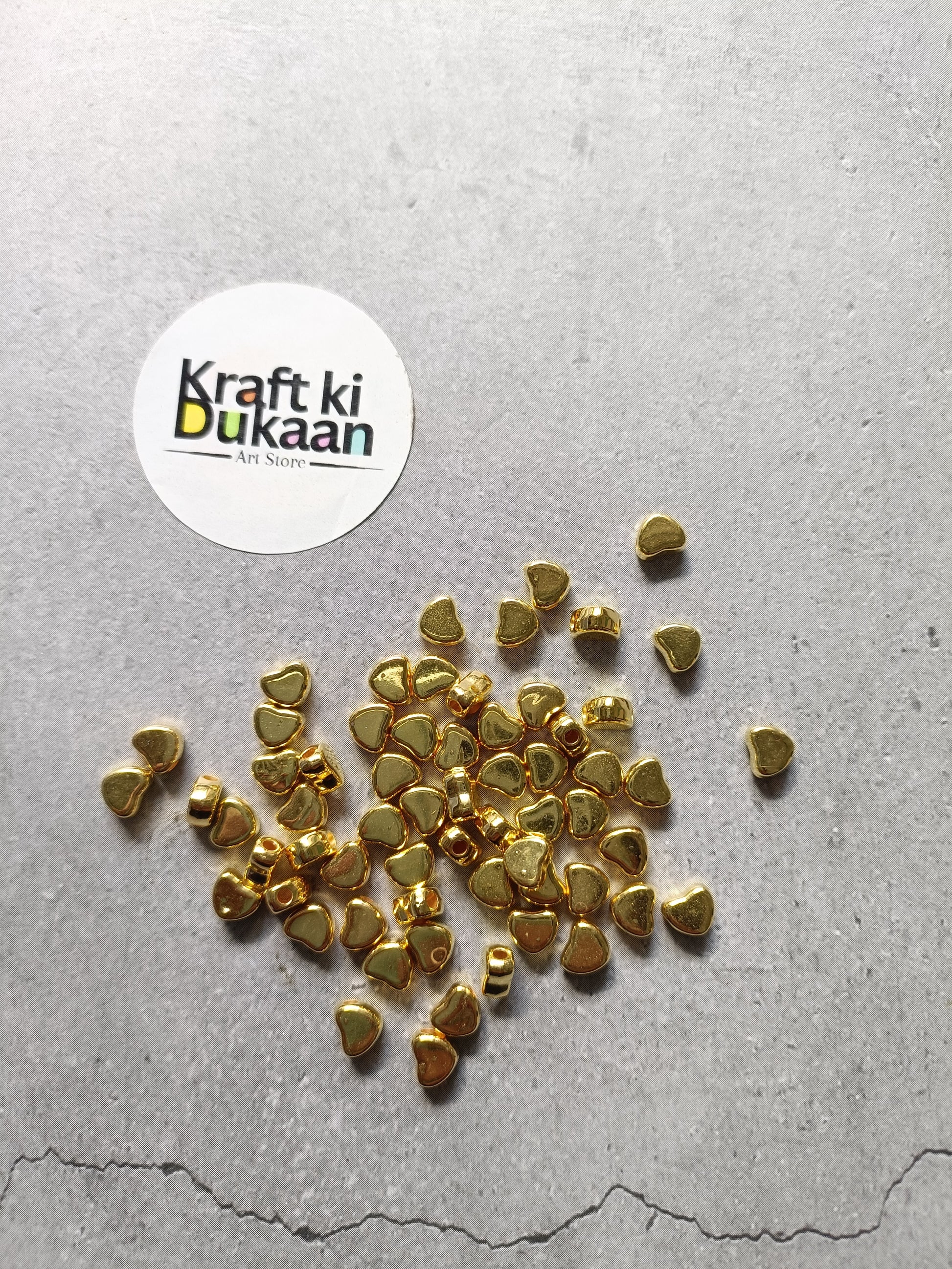 Golden heart-shaped small beads scattered, tiny metal craft pieces.