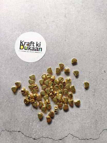Golden heart-shaped small beads scattered, tiny metal craft pieces.