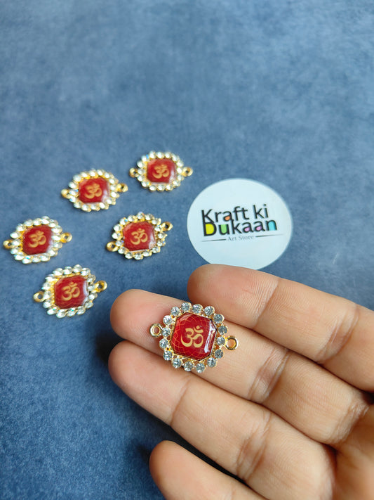 Gold-tone rakhi bracelet pendant with red Om 3 motif, shown in hand