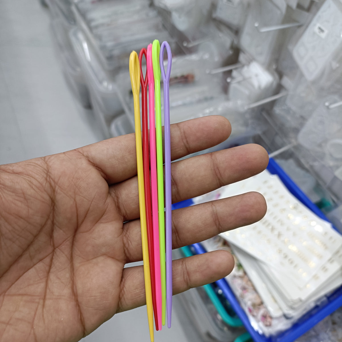 Set of five crochet needles in assorted colors, shown on hand
