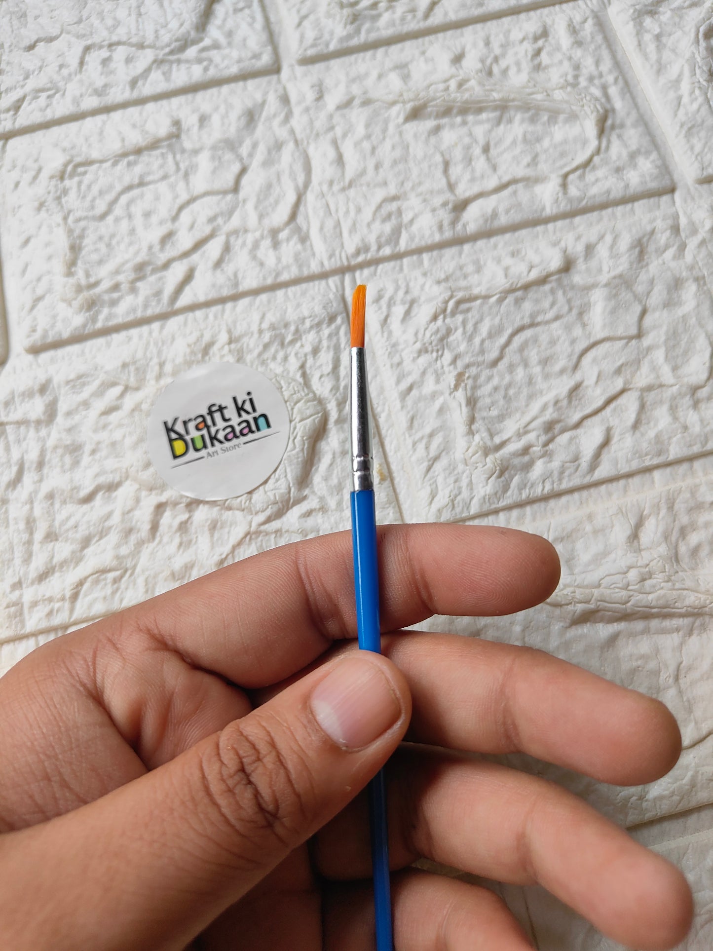 Round artist paint brush with blue handle, silver ferrule, and orange bristle tip