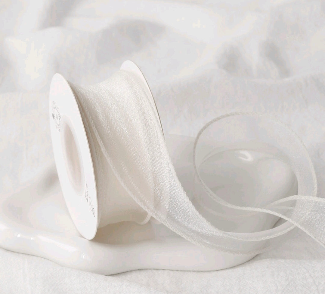 White sheer net ribbon on a spool, fine mesh texture, looped ribbon length
