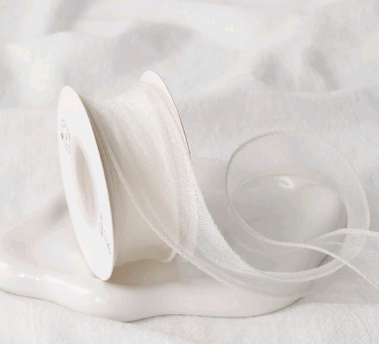 White sheer net ribbon on a spool, fine mesh texture, looped ribbon length