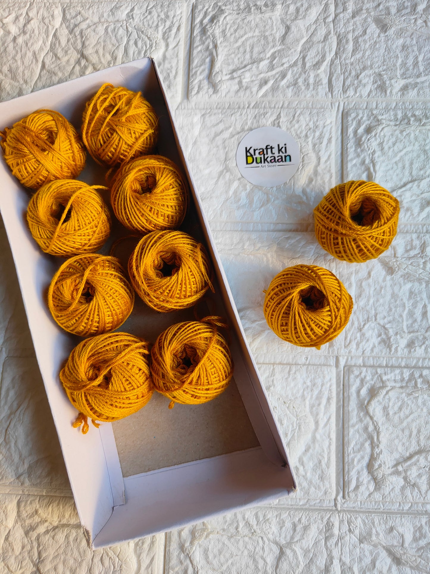 Rakhi thread roll with yellow-orange yarn balls and loose thread ends