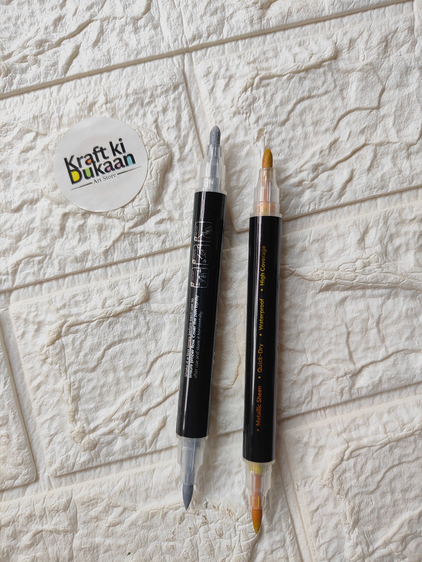 Dual-tip metallic acrylic markers with caps on, gold and silver tips visible