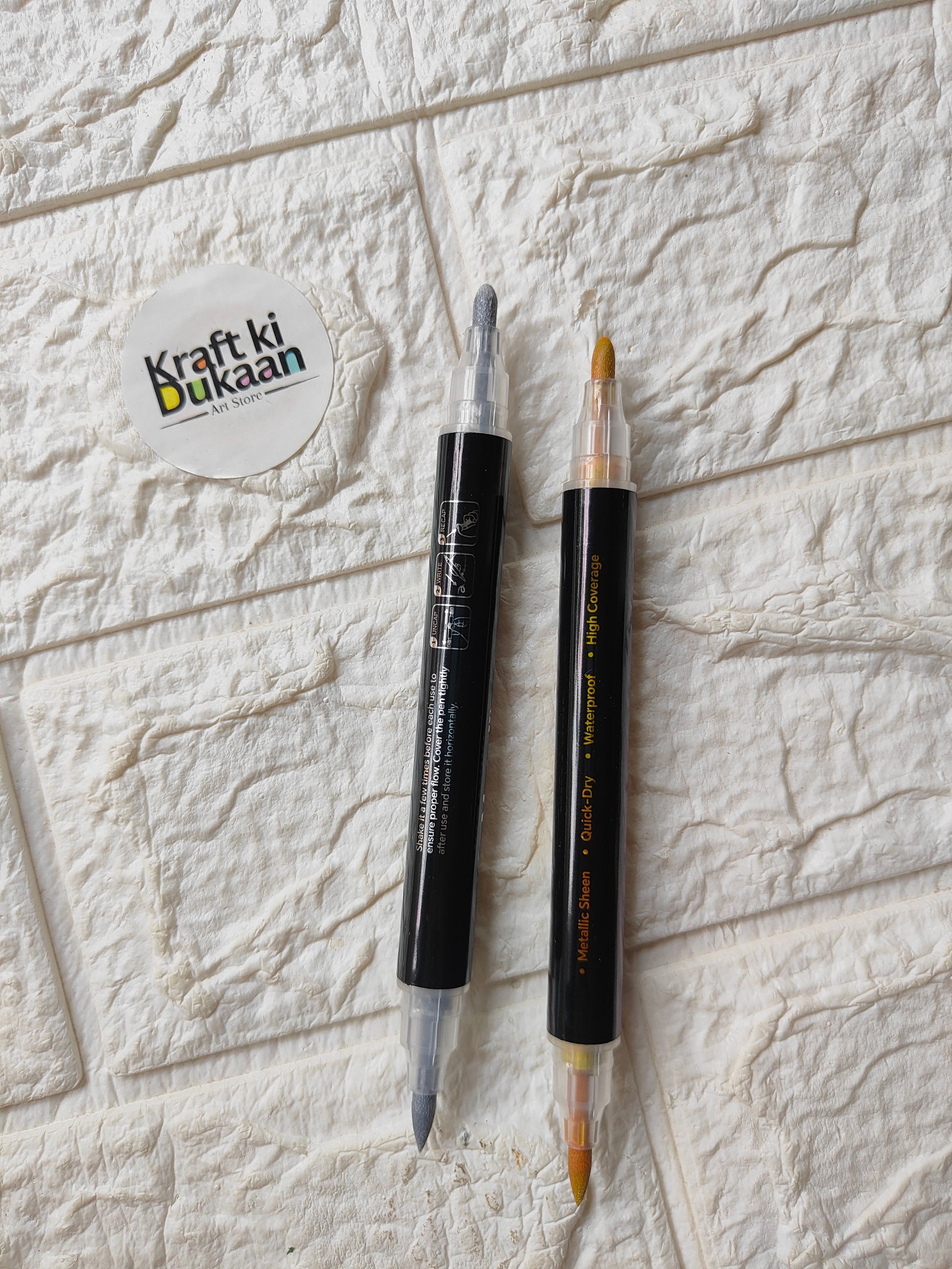 Dual-tip metallic acrylic markers with caps on, gold and silver tips visible