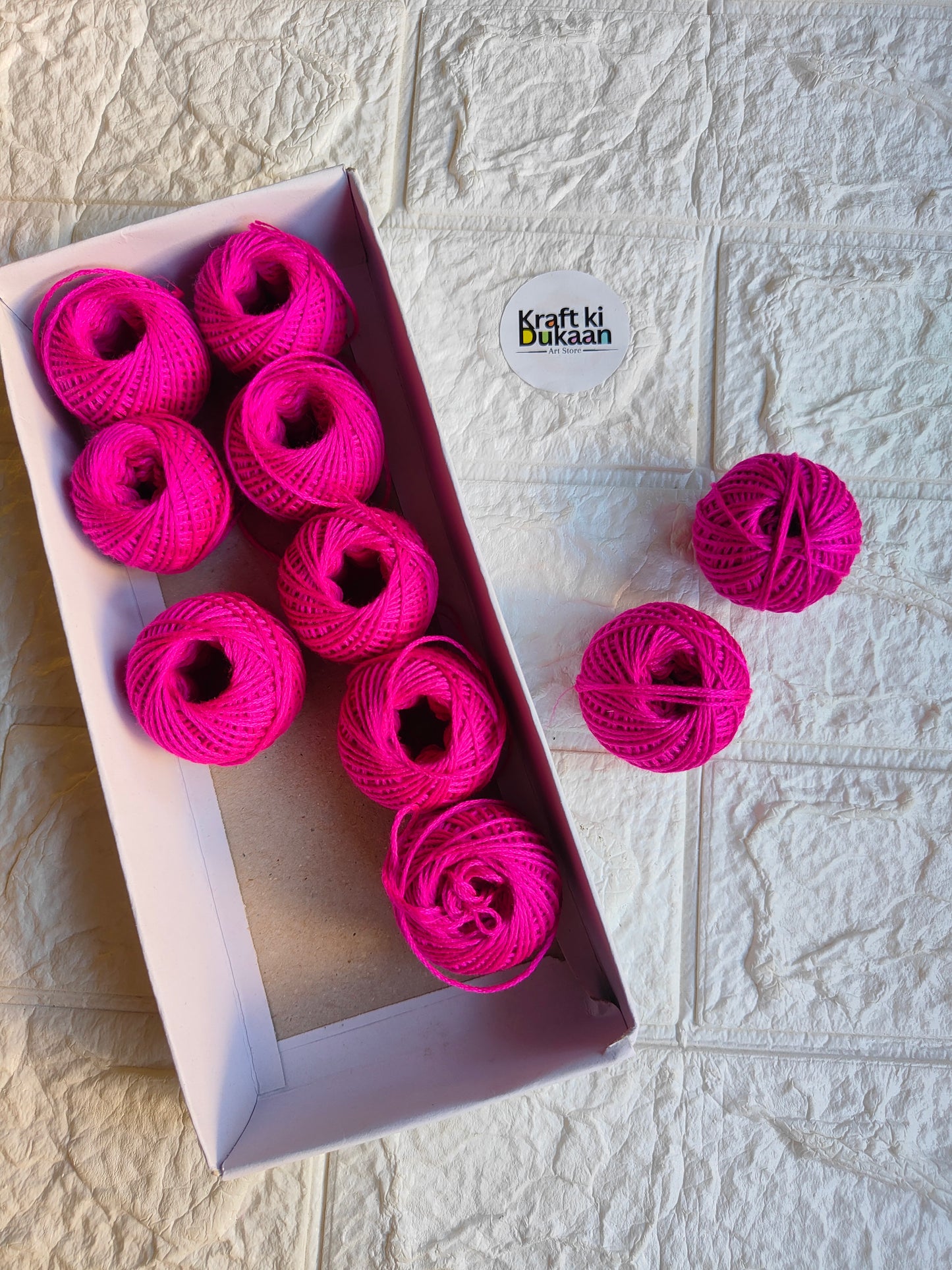 Rakhi thread roll with bright pink yarn balls in an open box and one loose ball