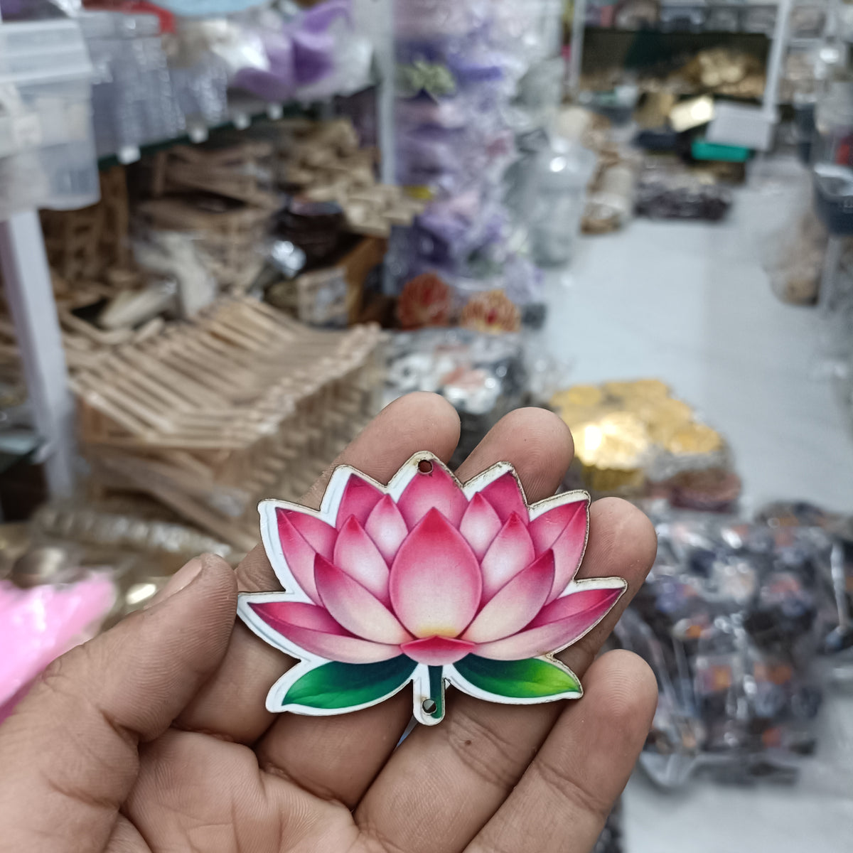 Pink lotus flower MDF cutout with green leaves and hanging hole, held in hand
