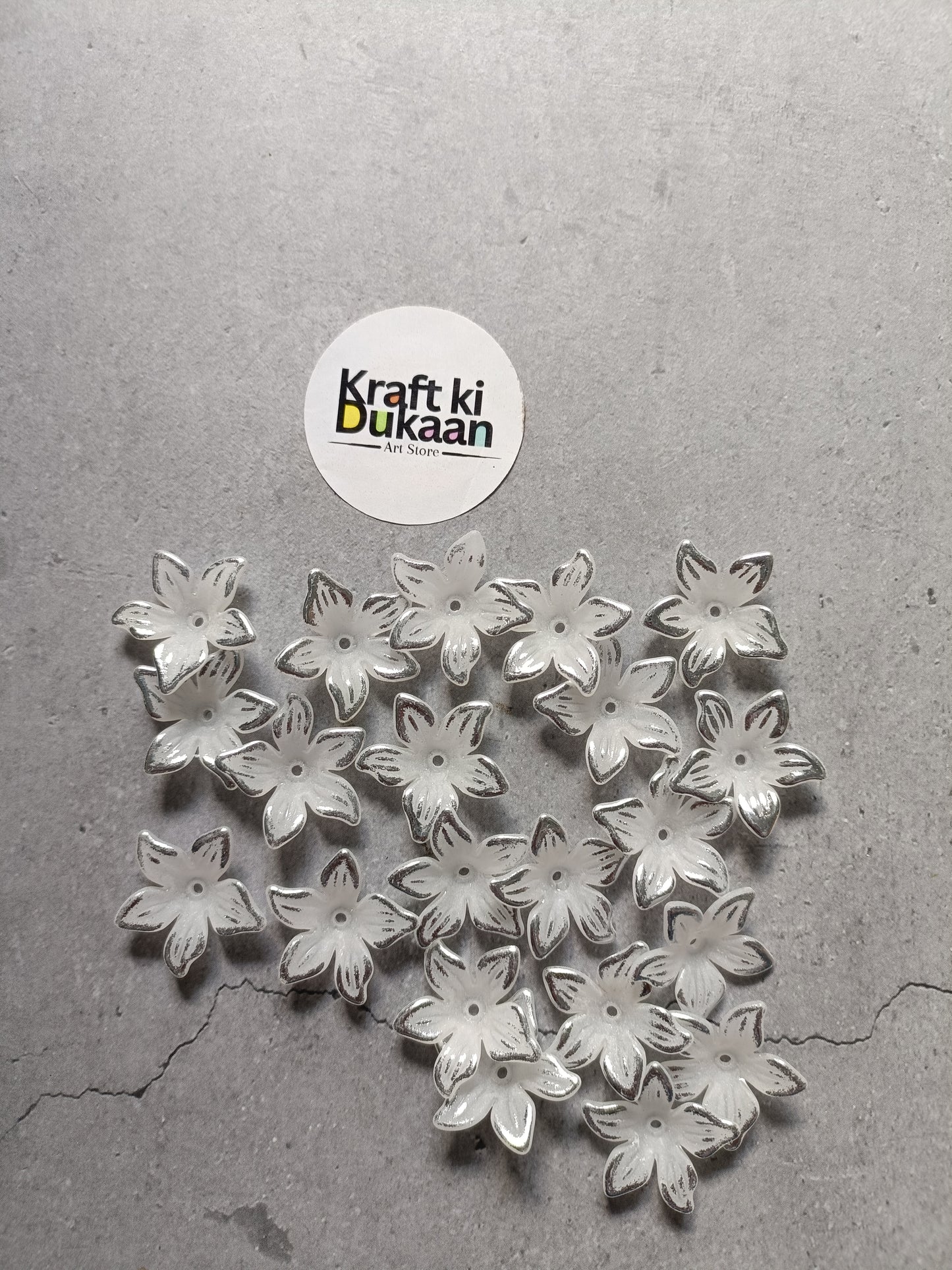 Pile of silver flower-shaped beads with embossed petals on flat back