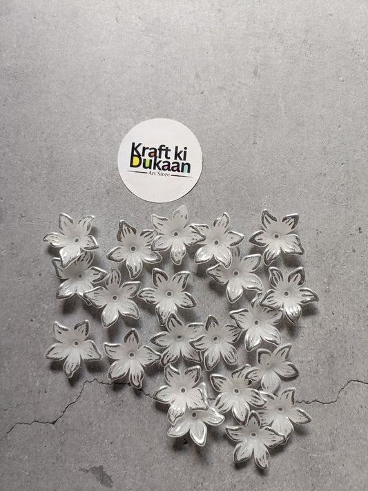 Pile of silver flower-shaped beads with embossed petals on flat back